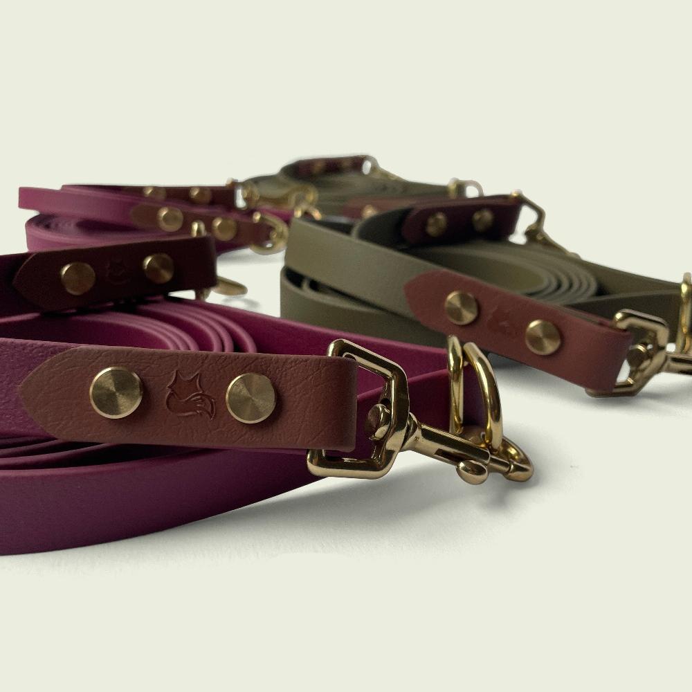 Close up of Jindo Hands-Free leashes in Burgundy Wine and Olive Green with medium brown accent biothane and gold hardware