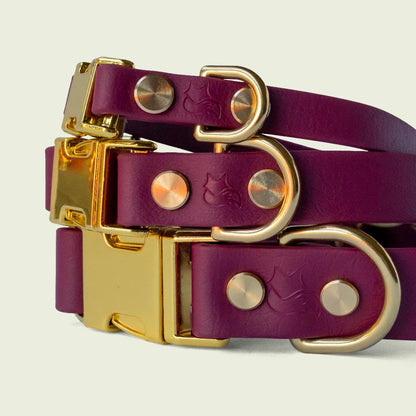 Stack of luxurious burgundy dog collars in 1/2, 3/4, and 1 inch wide, with gold hardware, showcasing premium style and durability.